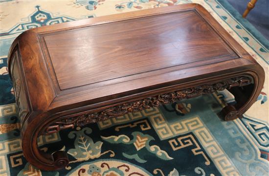 A Chinese carved hardwood low table on scrolled ends, 97cm wide